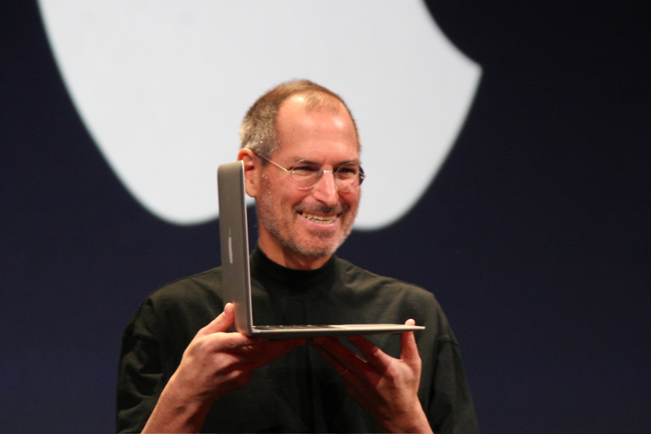 Steve Jobs holding a MacBook